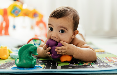 Actor portrayal of an infant with a teething toy in their mouth